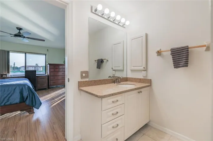 Ensuite bathroom featuring vanity, ceiling fan, and light wood-style floors
