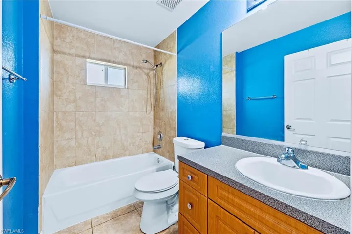 Full bathroom with tile patterned flooring, vanity, tiled shower / bath combo, and toilet