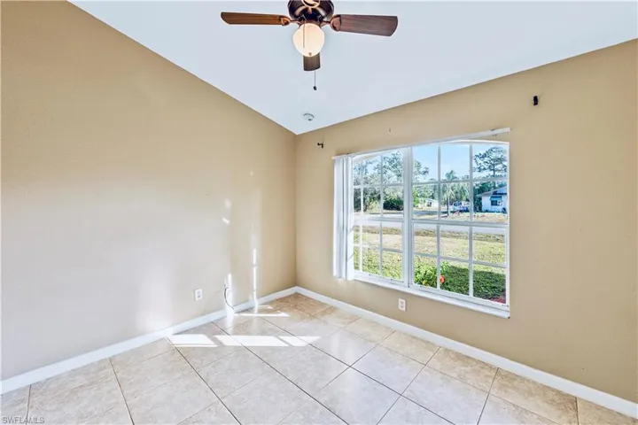 Tiled spare room featuring ceiling fan and lofted ceiling