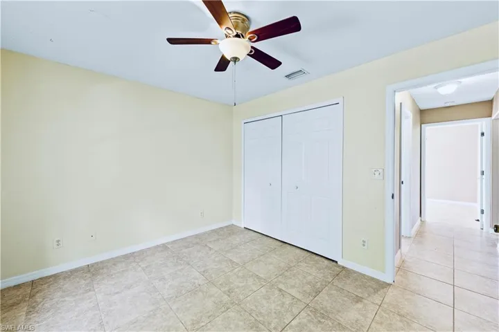 Unfurnished bedroom featuring ceiling fan, light tile patterned floors, and a closet