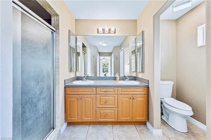 Bathroom with tile patterned flooring, vanity, toilet, and walk in shower
