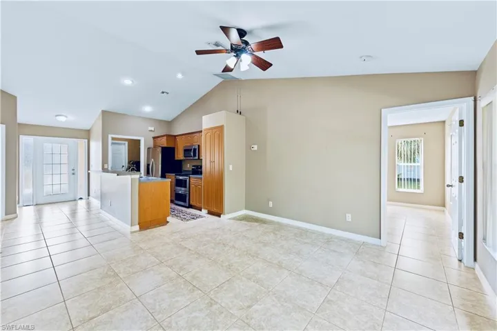 Kitchen with appliances with stainless steel finishes, ceiling fan, light tile patterned floors, a center island, and lofted ceiling