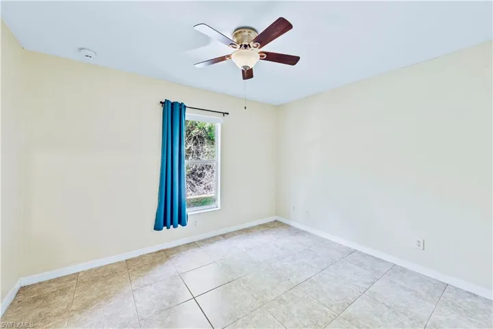 Tiled empty room featuring ceiling fan