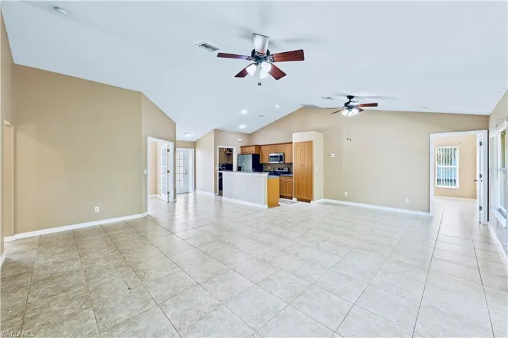 Unfurnished living room featuring light tile patterned floors, vaulted ceiling, and ceiling fan