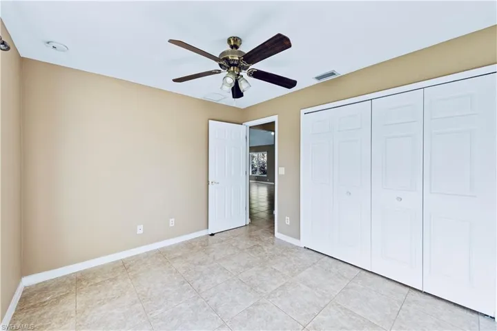 Unfurnished bedroom with ceiling fan, a closet, and light tile patterned floors