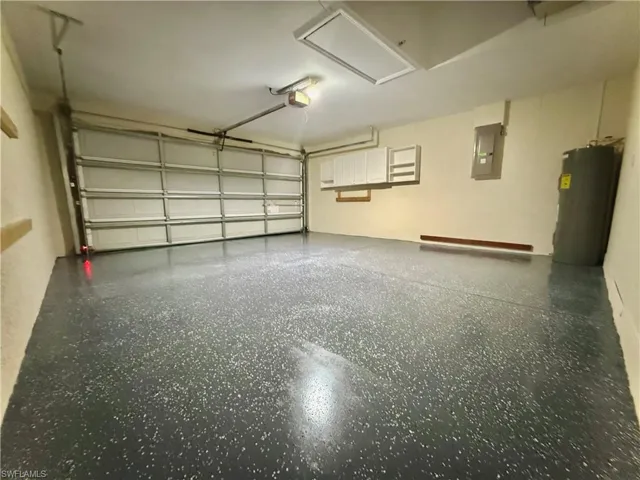 Garage featuring electric panel, water heater, and a garage door opener