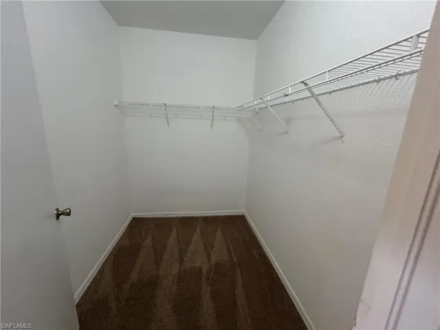 Walk in closet featuring dark carpet