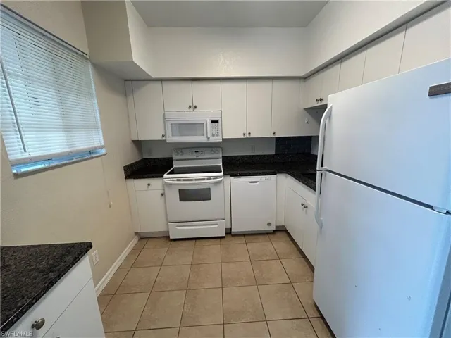 Kitchen with white appliances, white cabinetry, and light tile patterned floors