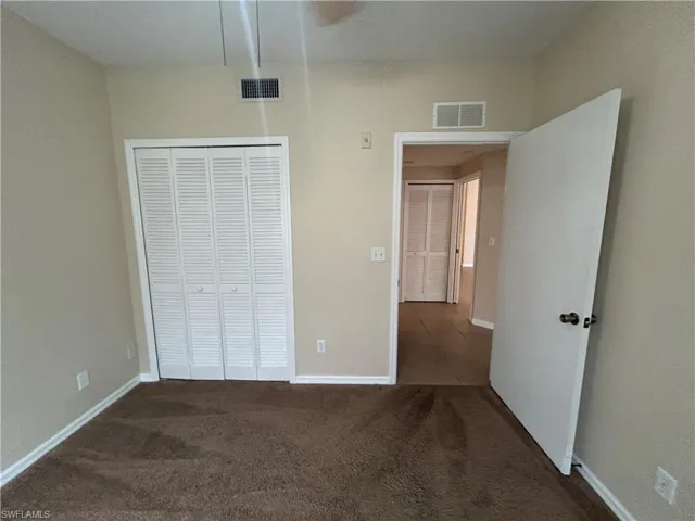 Unfurnished bedroom with dark carpet and a closet