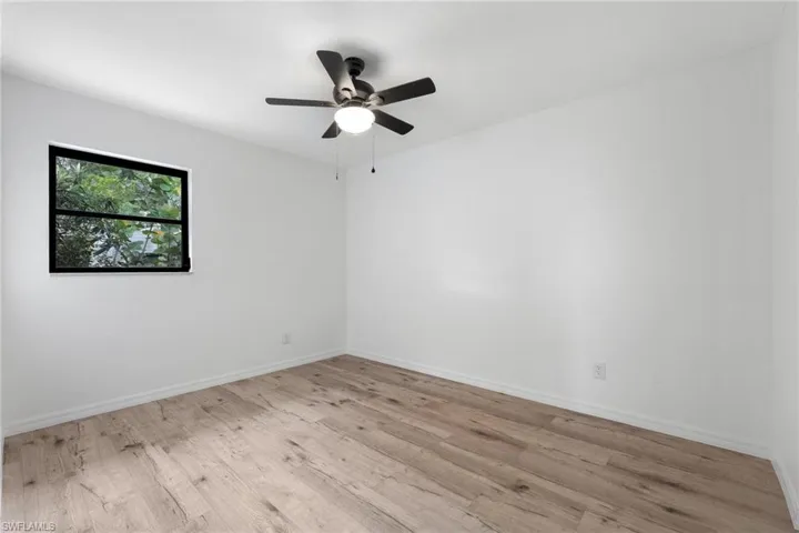 Spare room featuring light wood-style flooring, ceiling fan, and baseboards