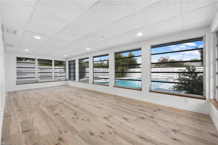Unfurnished room with a paneled ceiling, wood finished floors, baseboards, and visible vents