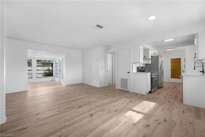 Unfurnished living room with light wood finished floors, visible vents, and a sink