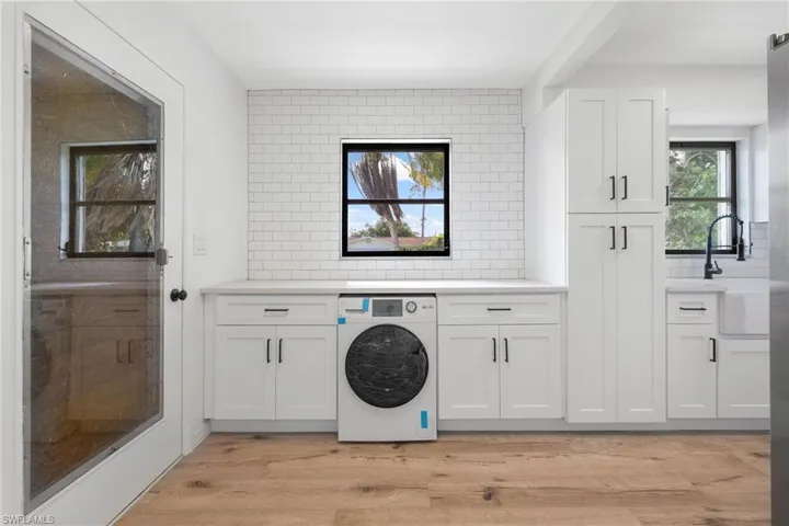 Laundry area featuring light wood-style flooring, a sink, cabinet space, and washer / dryer