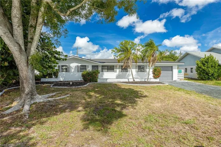 Single story home featuring a garage, aphalt driveway, and a front yard