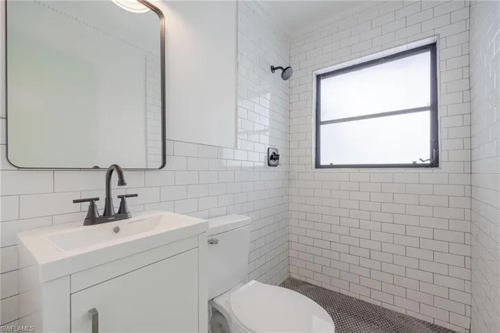 Master Bathroom with tasteful backsplash, tiled shower, vanity, toilet, and tile walls