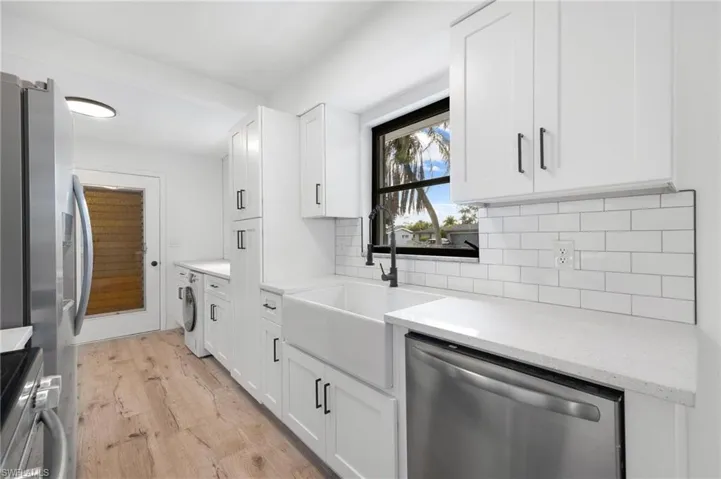 Kitchen featuring white cabinets, washer / clothes dryer, a sink, and appliances with stainless steel finishes