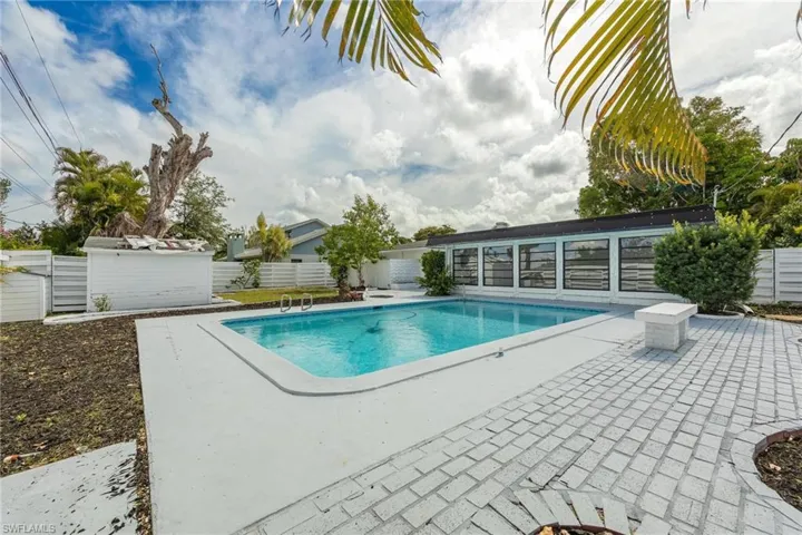 View of swimming pool featuring a patio area, fence, a fenced in pool, and an outbuilding