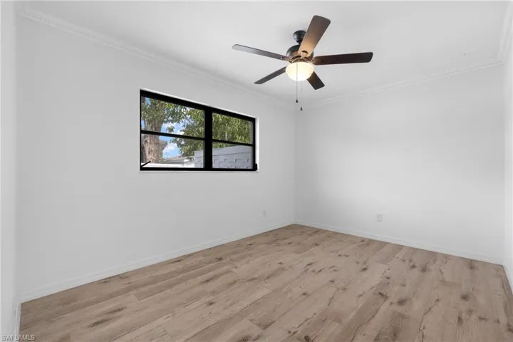 Unfurnished room featuring ornamental molding, baseboards, a ceiling fan, and wood finished floors