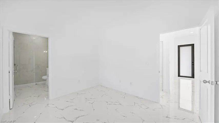 Spare room featuring light marble finish flooring and baseboards