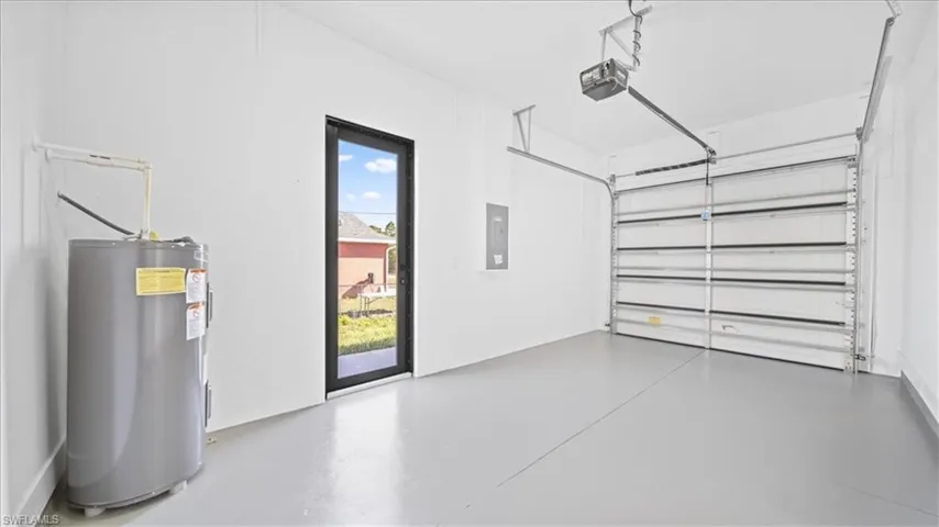 Garage with electric water heater, electric panel, and a garage door opener