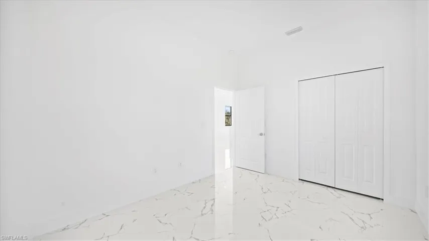 Unfurnished bedroom featuring a closet and light marble finish floors