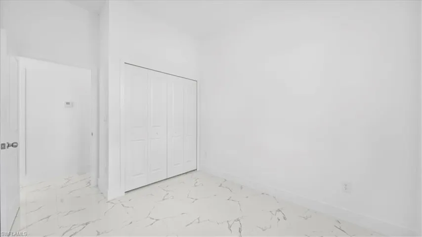 Unfurnished bedroom with a closet and light marble finish floors