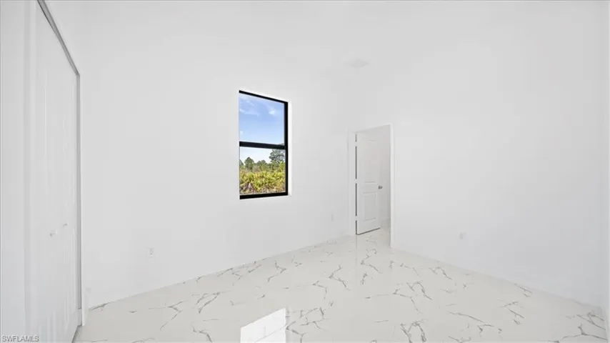 Unfurnished bedroom featuring light marble finish floors and a closet