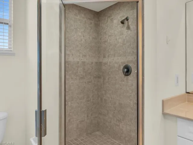 Bathroom featuring toilet, vanity, and an enclosed shower