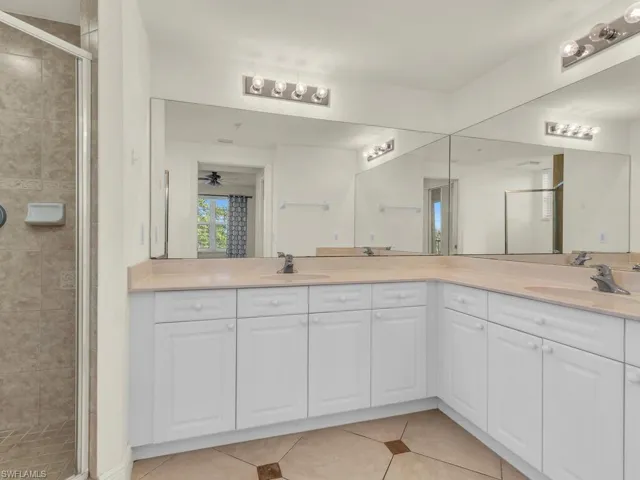 Bathroom with an enclosed shower, ceiling fan, dual bowl vanity, and tile patterned flooring