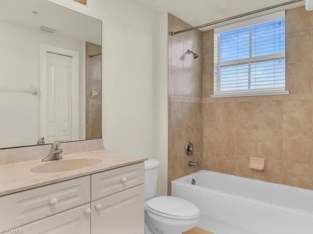 Full bathroom with vanity, tiled shower / bath combo, and toilet
