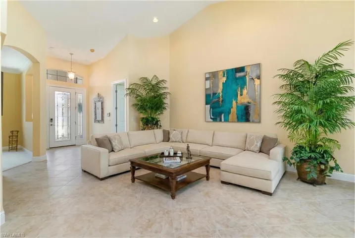 Virtually Edited. Living area with arched walkways, light tile patterned floors, and lofted ceiling