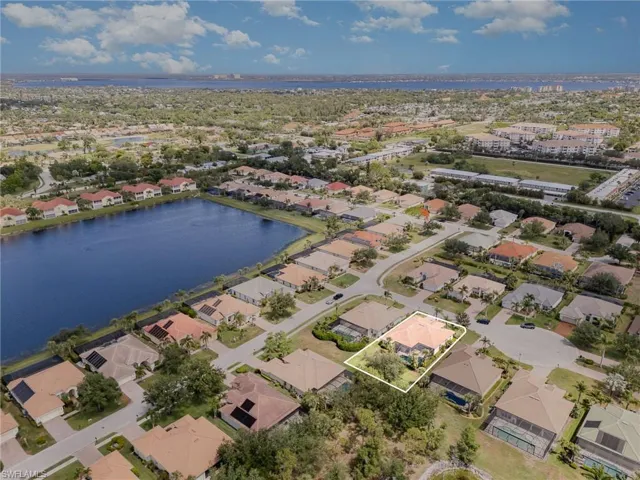 Aerial view of property and surrounding area featuring a nearby body of water, property boundaries highlighted, and nearby suburban area