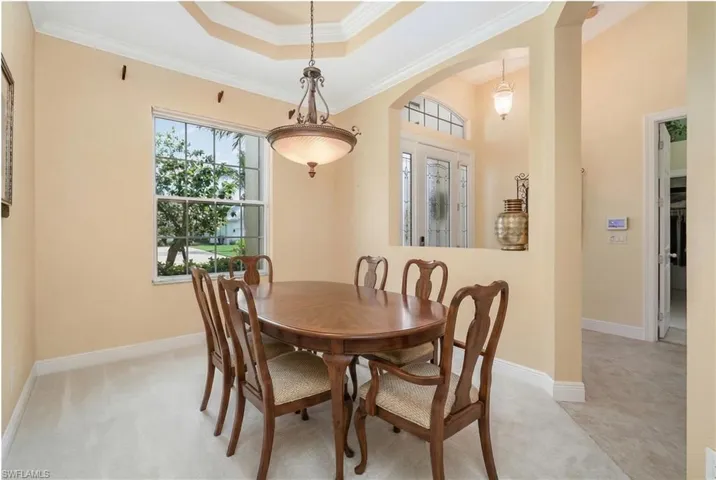 Virtually Edited. Dining area with crown molding, arched walkways, and a raised ceiling
