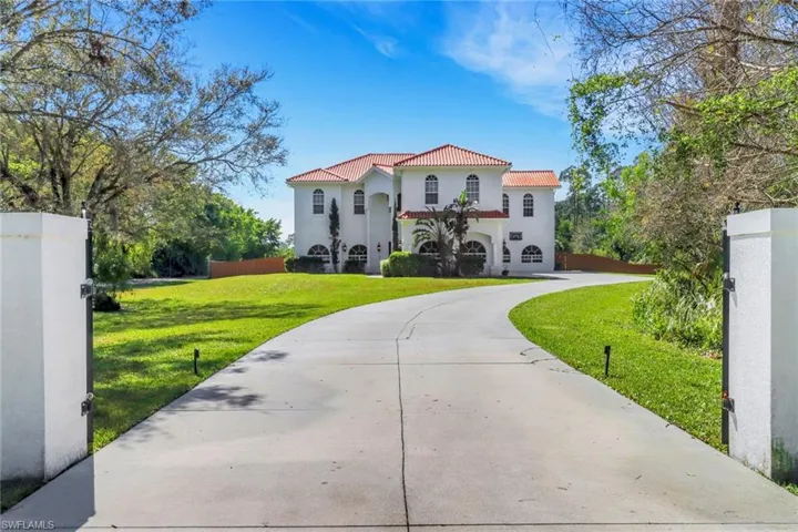 Mediterranean / spanish-style house featuring driveway, a tiled roof, fence, a front yard, and stucco siding
