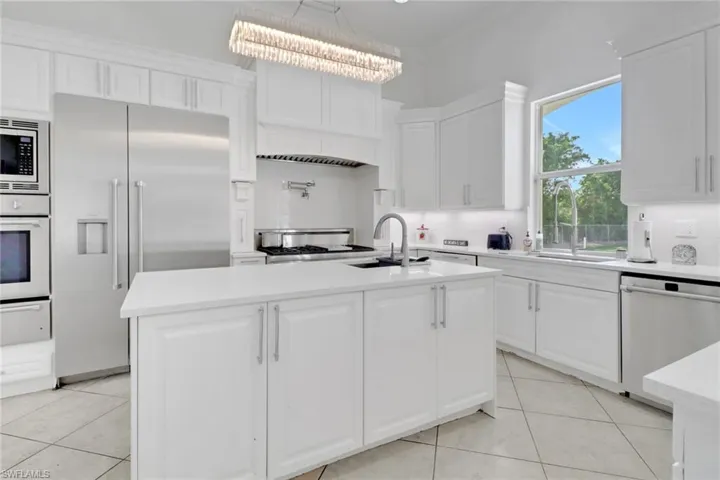 Kitchen featuring white cabinets, appliances with stainless steel finishes, light countertops, and a sink