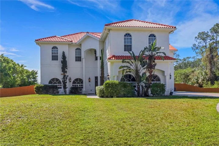 Mediterranean / spanish-style house with a tiled roof, a front yard, and fence