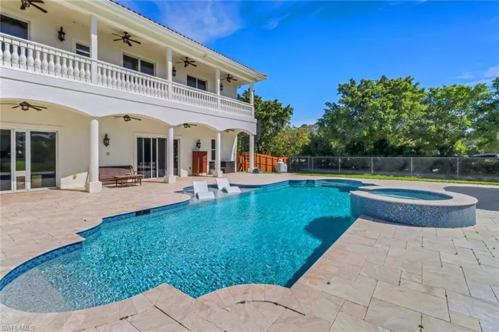 View of swimming pool with ceiling fan, a pool with connected hot tub, a patio, and fence