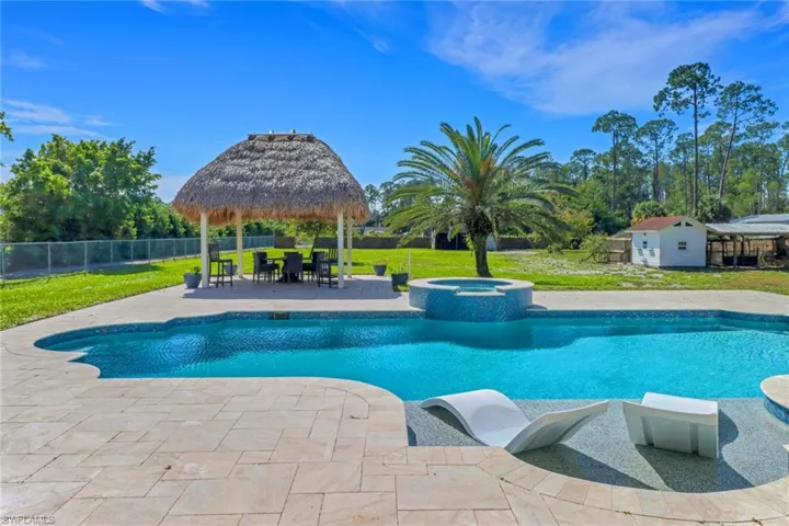 View of pool featuring a lawn, a pool with connected hot tub, a patio, fence, and a gazebo