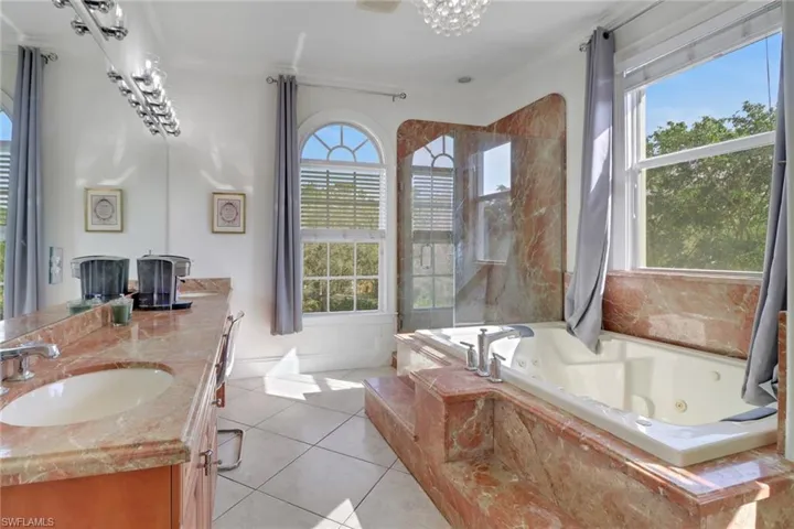 Bathroom featuring a whirlpool tub, vanity, and tile patterned flooring