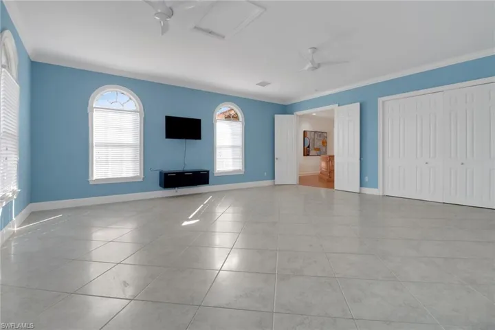 Unfurnished living room with tile patterned floors, baseboards, ceiling fan, and crown molding