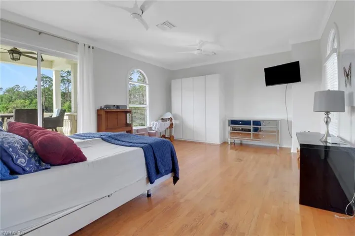Bedroom featuring visible vents, crown molding, ceiling fan, light wood-style floors, and access to outside