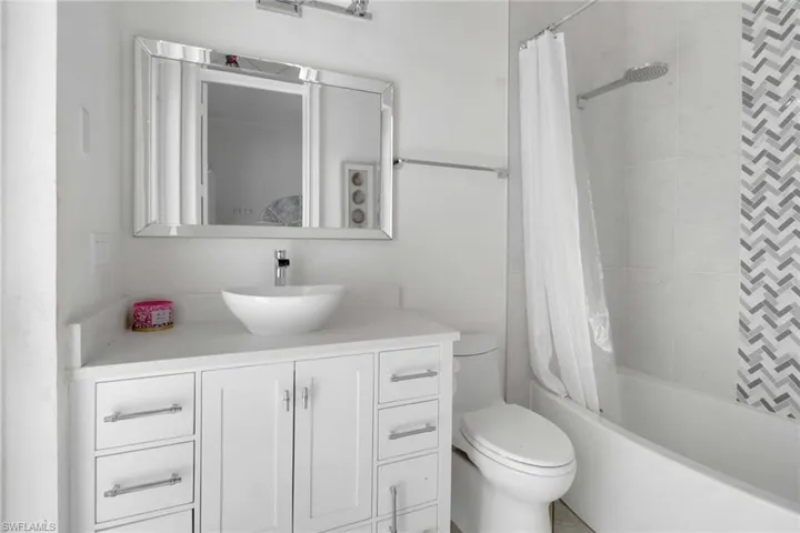 Bathroom with toilet, shower / bathtub combination with curtain, and vanity