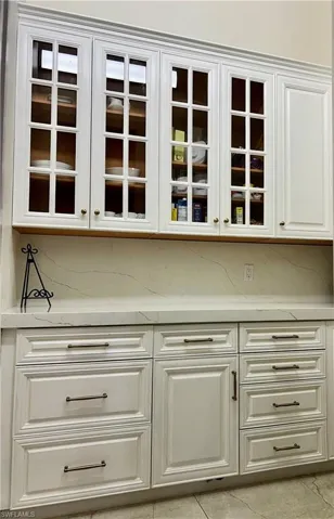 Bar with light stone countertops and white cabinets