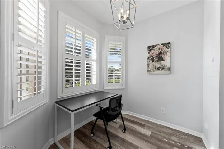 Office area featuring wood-type flooring and an inviting chandelier