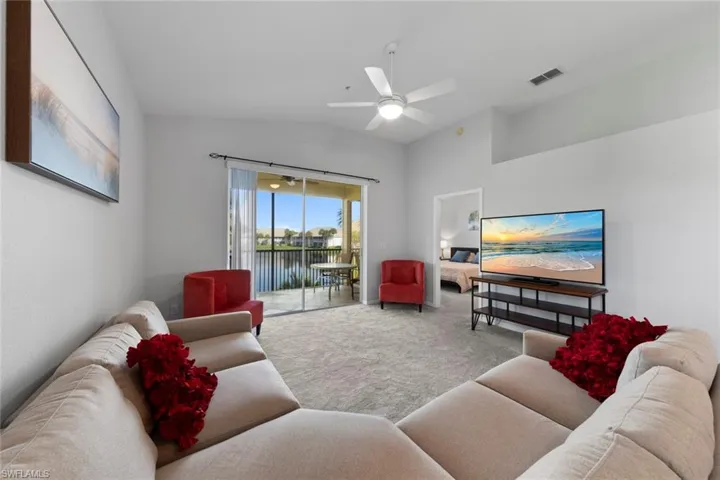Carpeted living room featuring lofted ceiling and ceiling fan