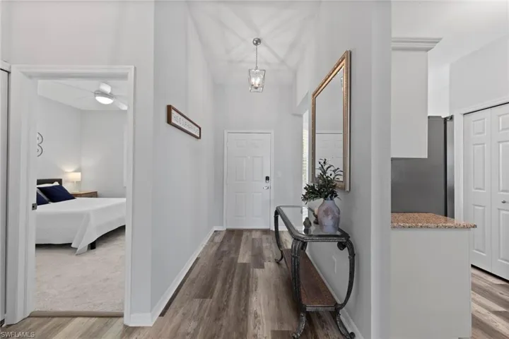 Entryway with light wood-type flooring and ceiling fan with notable chandelier