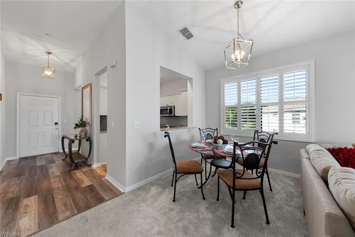 Dining space with vaulted ceiling, dark hardwood / wood-style flooring, and a notable chandelier
