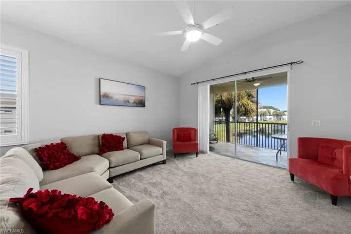 Carpeted living room featuring ceiling fan and vaulted ceiling