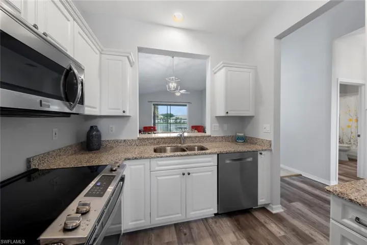 Kitchen with appliances with stainless steel finishes, dark hardwood / wood-style flooring, sink, and white cabinets