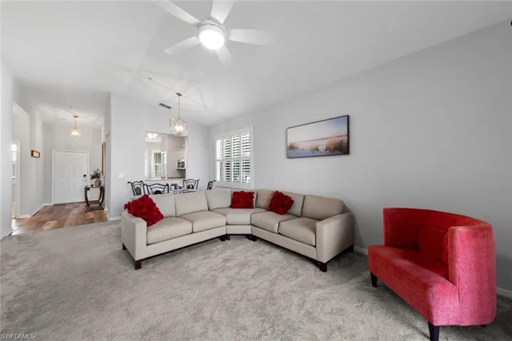 Living room featuring lofted ceiling, ceiling fan, and wood-type flooring